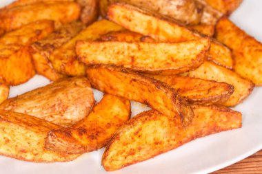 Tabaklarında farklı baharatlar, seçici bir odak noktasında yakın plan kesilmiş fırında patates parçaları.