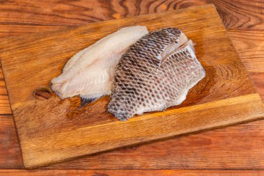 İki buzu çözülmüş çiğ İspanyol fileto kemiksiz balık leşi şeklinde kırsal bir masada eski bir meşe kesme tahtasının üzerinde.