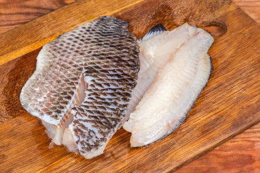 İki buzu çözülmüş çiğ İspanyol fileto kemiksiz balık leşi şeklinde kırsal bir masada eski bir meşe kesme tahtasının üzerinde.