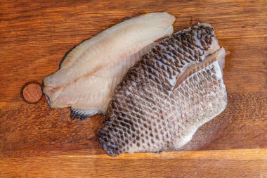 İki buzu çözülmüş çiğ dourade fileto. Kemiksiz balık leşi şeklinde. Eski bir meşe kesme tahtasının üzerinde.