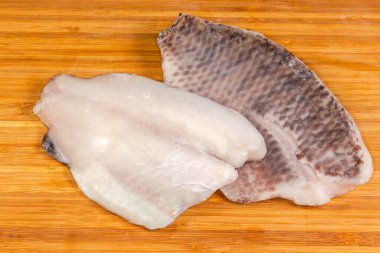 Bambu kesme tahtasındaki beyaz bir tabakta buz jöleli iki çiğ kemiksiz fileto.