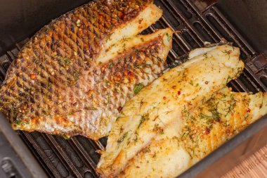 Izgaranın çekmecesinde baharatlarla ızgara yapılmış iki kemiksiz fileto.