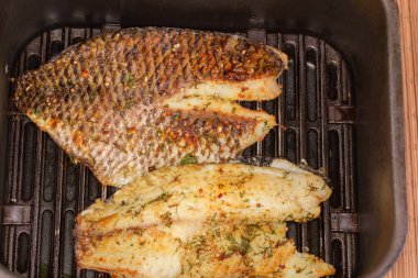 Izgaranın çekmecesinde baharatlarla ızgara yapılmış iki kemiksiz fileto, yakın çekim.