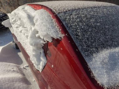 Kar ve yaban ördeğinin dokusu, kar fırtınası sonrası kar altında kalmış kırmızı bir arabanın yan ve arka tarafına yerleşmiş.