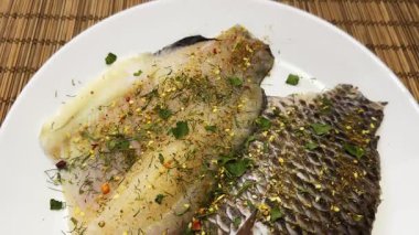 Çiğ dourade fileto beyaz bir tabakta baharat serpiştirilmiş