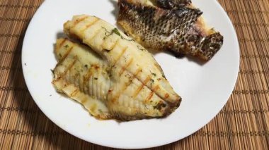 Izgara dourade fileto beyaz tabak üzerinde bambu servis altlığı