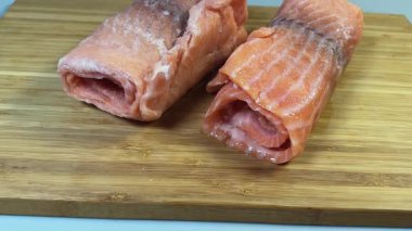 Çiğ donmuş somon dilimleri kesme tahtasına sarılmış.