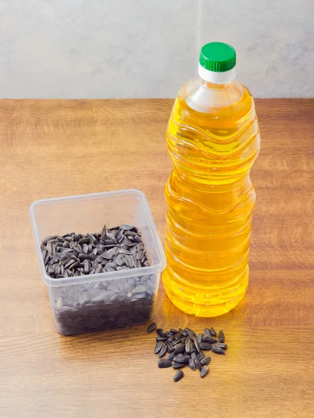 Graines de tournesol dans un plateau en plastique et bouteille d'huile de tournesol — Photo