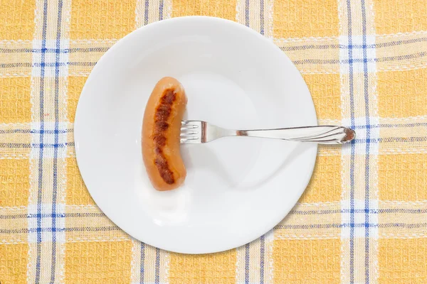 Salchicha a la parrilla empalada en un tenedor en un plato blanco — Foto de Stock
