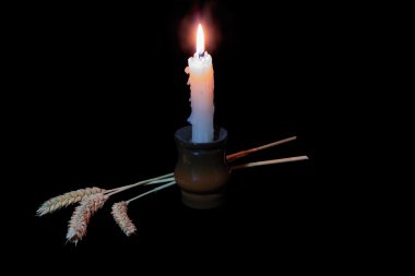 Candle and three ears of wheat on a dark backgroun clipart