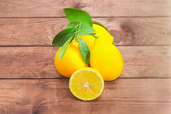 Несколько целых лимонов и один лимон, разрезанный пополам — стоковое фото