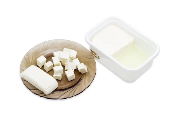 Container of feta cheese and slised cheese on a saucer — Φωτογραφία Αρχείου