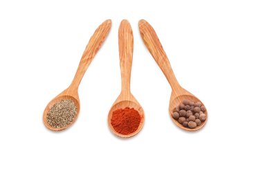 Different kinds of pepper in three wooden spoons
