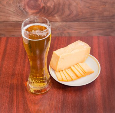 Beer glass with lager beer and cheese on saucer