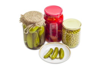 Pickled cucumbers on saucer and pickled vegetables in glass jars