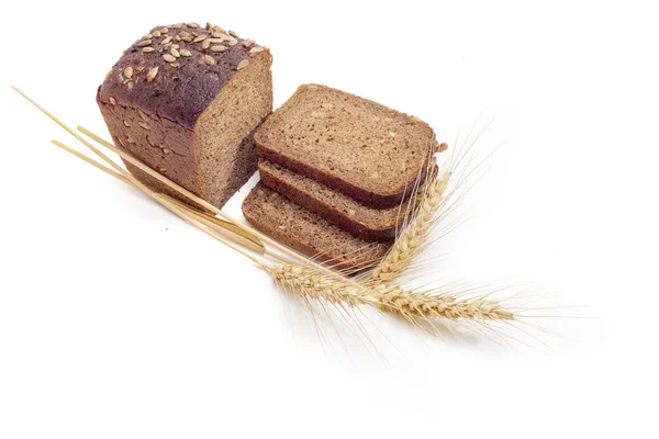 Mörkt bröd med korn av solrosor och vete spikar — Stockfoto