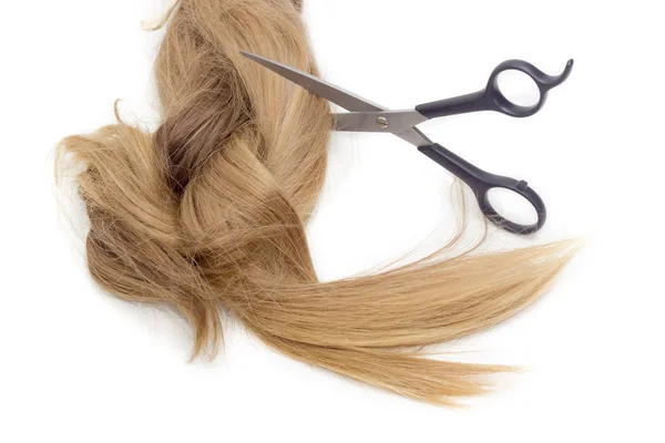 Hairdressers scissors against the backdrop of strand of female h — Stock Photo, Image