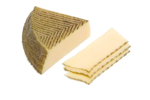Piece and several slices of Spanish cheese on light background — Stock Photo, Image