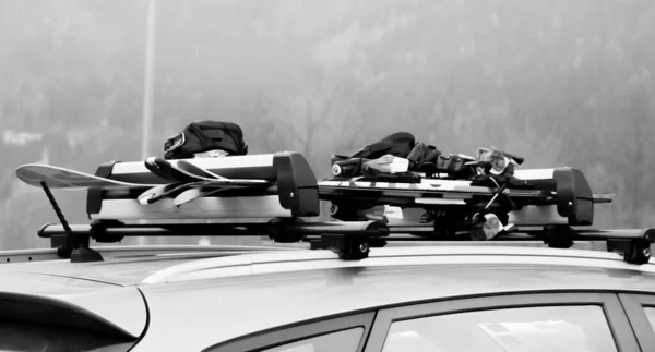 两对滑雪板和一块雪板在车顶上 图库照片