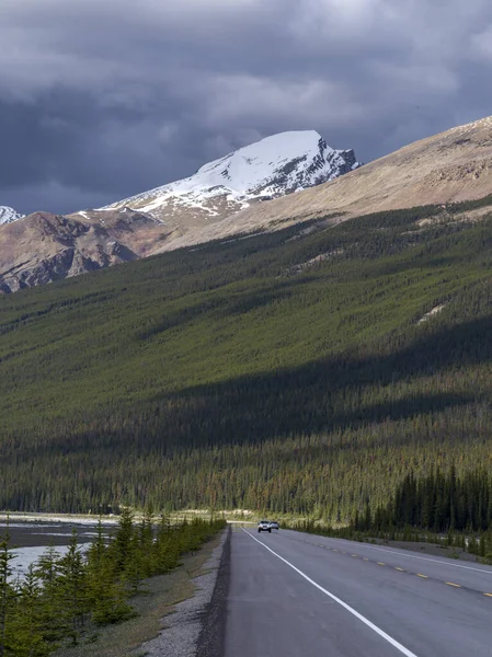 Car moving on highway with mountain range in the background, Icefield Parkway, Alberta, Canada