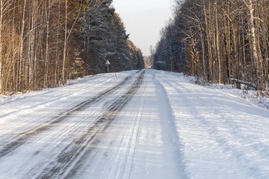 Turuncu günbatımı arka planında, kışın ıssız bir yol.