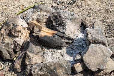 Gri ve kahverengi büyük taşlar ve odun ormandaki bir şöminede.