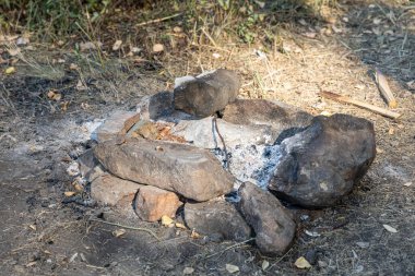 Gri ve kahverengi büyük taşlar ve beyaz kül ormanda bir şöminede
