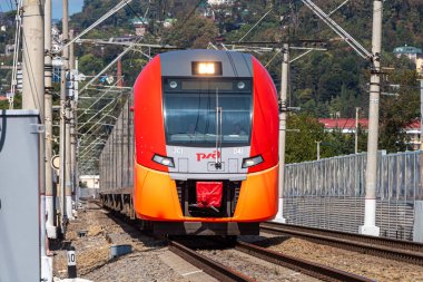 Sochi, Rusya - 09 09: 2020: Yazın yeni bir kırmızı ve turuncu elektrikli tren tren bir tren istasyonuna geliyor
