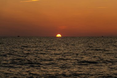 Güzel turuncu gün doğumu sahilin kenarında siyah gemi siluetleriyle