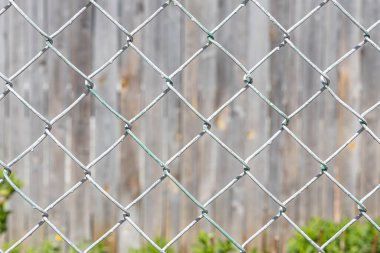 Beyaz metal bir kafesin Rhombic hücrelerinin dokusu gri ahşap arka plandaki yaz parkında güneşli bir günde bulunur.