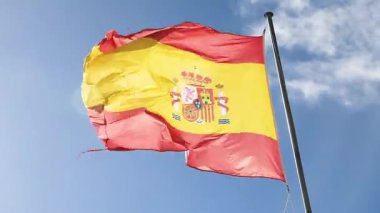 La Gineta, Albacete, İspanya - 11 Kasım 2025 İspanya ulusal bayrağı güneşli bir günde açık mavi bir gökyüzüne doğru dalgalanmaktadır.