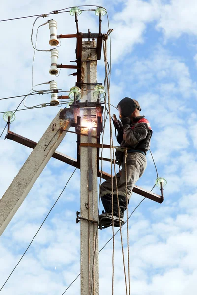 Electricien connecte des pièces métalliques boucle de terre sur un transmiss pôle Image En Vente