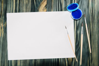 Boyalar, fırçalar, kağıt üzerinde ahşap masa