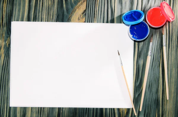 Verf, penselen, papier op de houten tafel — Stockfoto