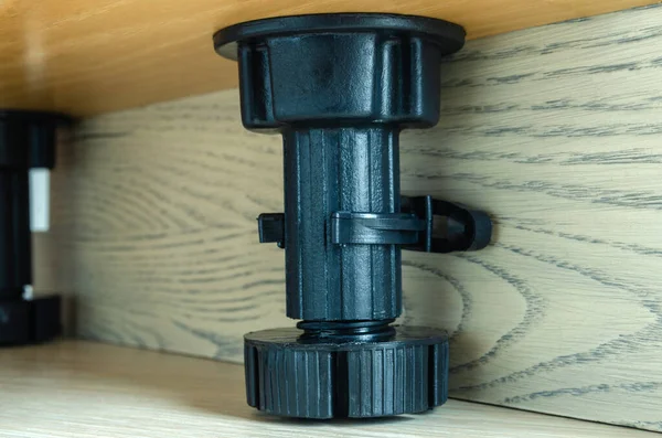 furniture black plastic support for kitchen set, on wooden background, close-up