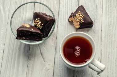 Siyah çay ve çikolatalı kekler, ahşap bir masada..