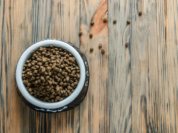 Full bowl of dog food close up on wooden background