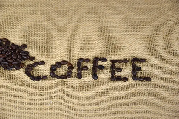 Wortkaffee in Kaffeebohnen auf Burlap — Stockfoto