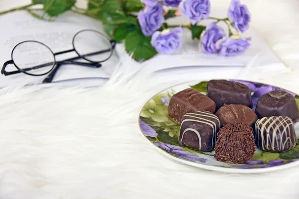 Fancy chocoladesuikergoed op witte vacht met boek — Stockfoto