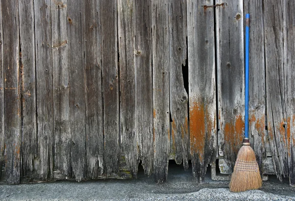 Oude bezem leunend op verweerde schuur gevelbekleding — Stockfoto