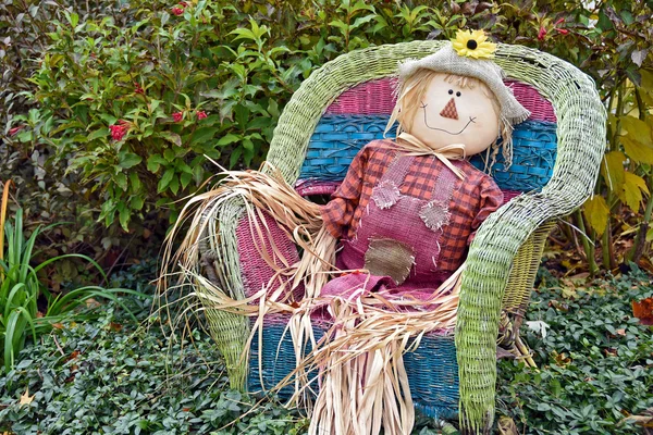 Fall scarecrow in sitting in wicker chair — Stock Photo, Image