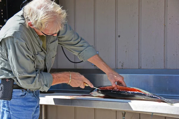 Мужчина чистит лосося — стоковое фото