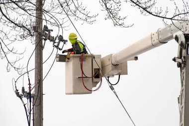 Elektrikçi asansör kovasında elektrik transformatörünü tamir ediyor.