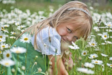 Yaban çiçeği tarlasında gülümseyen genç sarışın kız.