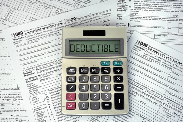 Deductible text on business calculator screen with 1040 Internal Revenue Tax Forms