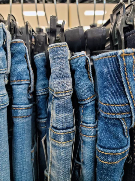 Zamknij Rząd Dżinsów Jeansowych Wiszących Plastikowych Hangarach Sklepie — Zdjęcie stockowe