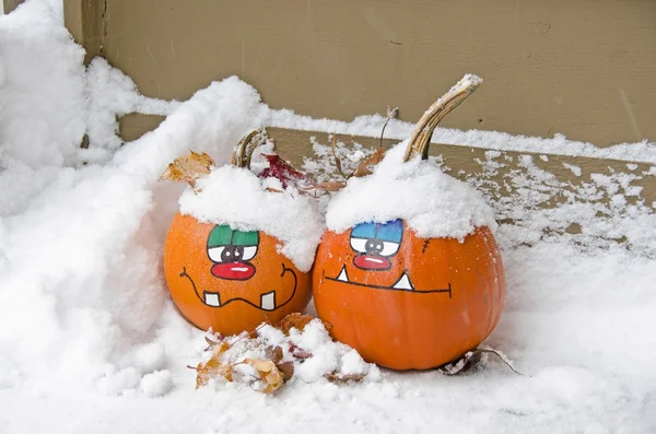 Pair of fun faces on Halloween pumpkins in snow — ストック写真