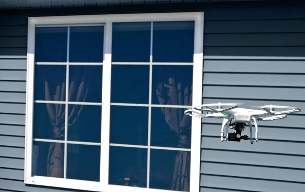 White drone with camera by house window — Stock Photo, Image