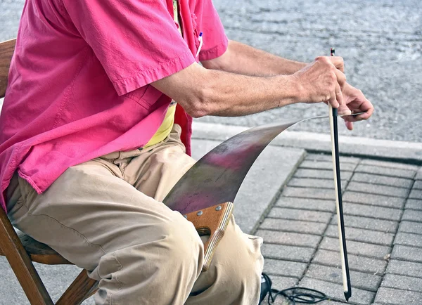 Viejo tocando una sierra musical — Foto de Stock