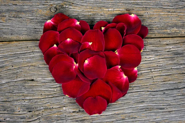 Srdce červené růžové okvětní lístky na rustikální dřevo — Stock fotografie